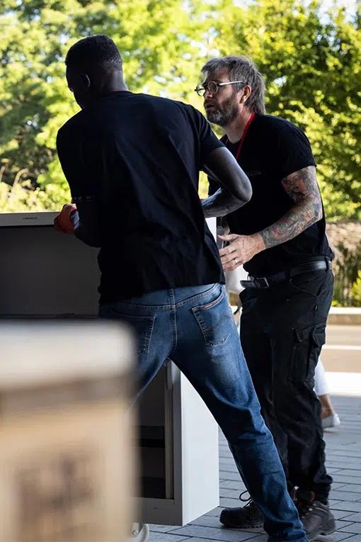 Techniciens Broke & Recycling déplaçant un meuble de bureau